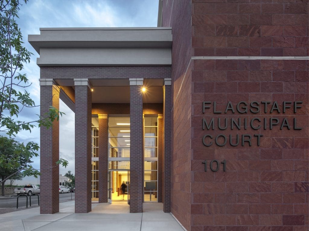Entrance to the City of Flagstaff Municipal Court Facility, winner of a Masonry Award, featuring tall columns, glass doors, and the address number 101 on a striking red brick facade.