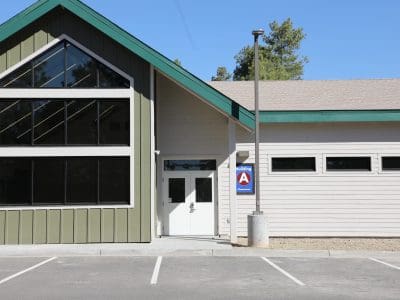 Exterior view of the Northland Preparatory Academy STEAM Building with large windows, a double door entrance, and an "A Classroom" sign, situated next to an empty parking lot.