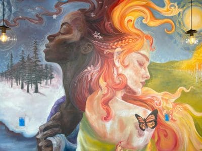 A mural shows two women back-to-back, one with dark skin and winter scenery, the other with light skin, fiery hair, and butterflies, representing contrasting seasons.