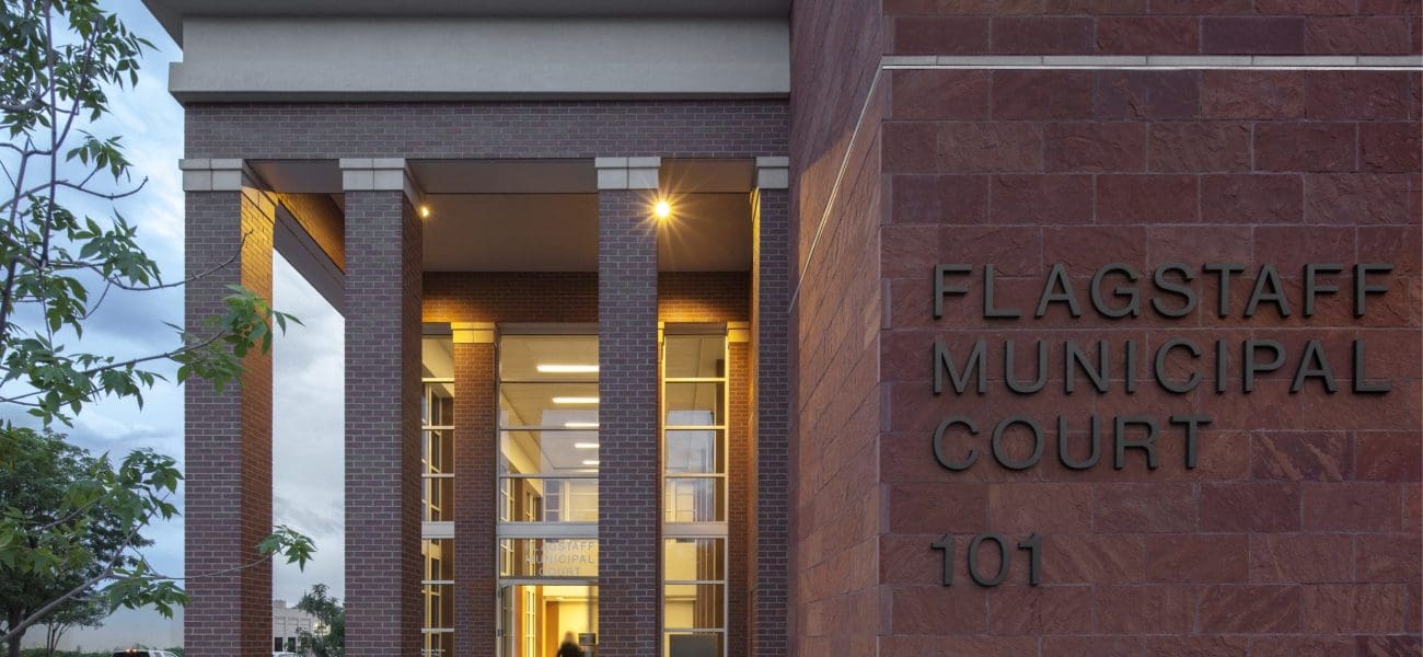 Entrance to the City of Flagstaff Municipal Court Facility, winner of a Masonry Award, featuring tall columns, glass doors, and the address number 101 on a striking red brick facade.