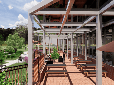 Outdoor patio with picnic tables, pergola structure, and people sitting; adjacent to a building with large windows, overlooking a landscaped park area.