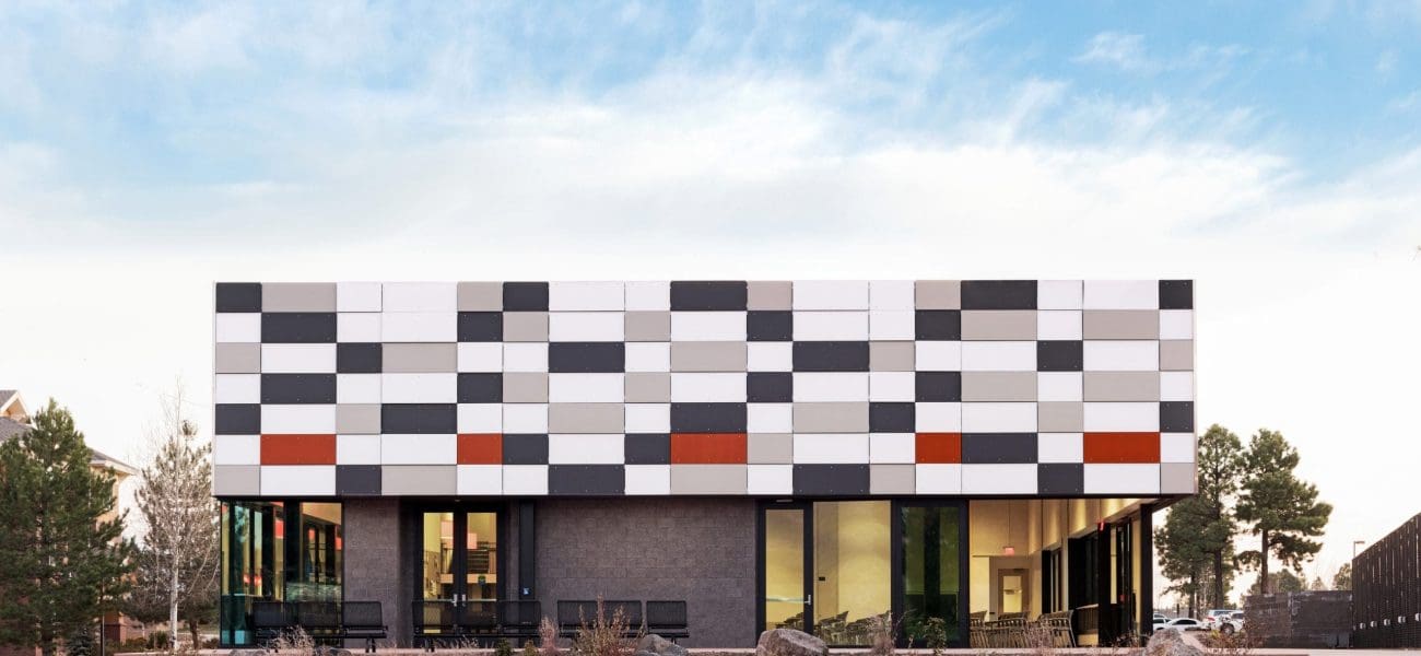 NAU IP ENR Award Modern building with a rectangular design and checkered facade of black, white, and gray panels, large windows, and a landscaped lawn—showcasing how Kinney is Building Better Together for a Greener Tomorrow in honor of Earth Day.