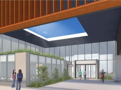 A modern building entrance with large glass windows, people walking and talking, greenery, and an open skylight above the courtyard.