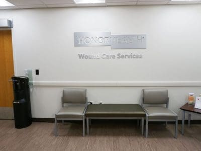 Waiting area at HonorHealth Wound Care Services with three chairs, a water dispenser, and informational pamphlets on a small table.