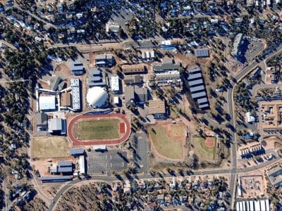 Aerial view of a school campus with a Payson USD PV System, running track, football field, baseball diamond, multiple buildings, and surrounding residential area.