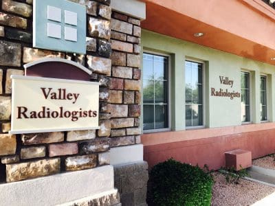 Exterior view of a medical office building with signs reading "Valley Radiologists" on the wall and next to the entrance.